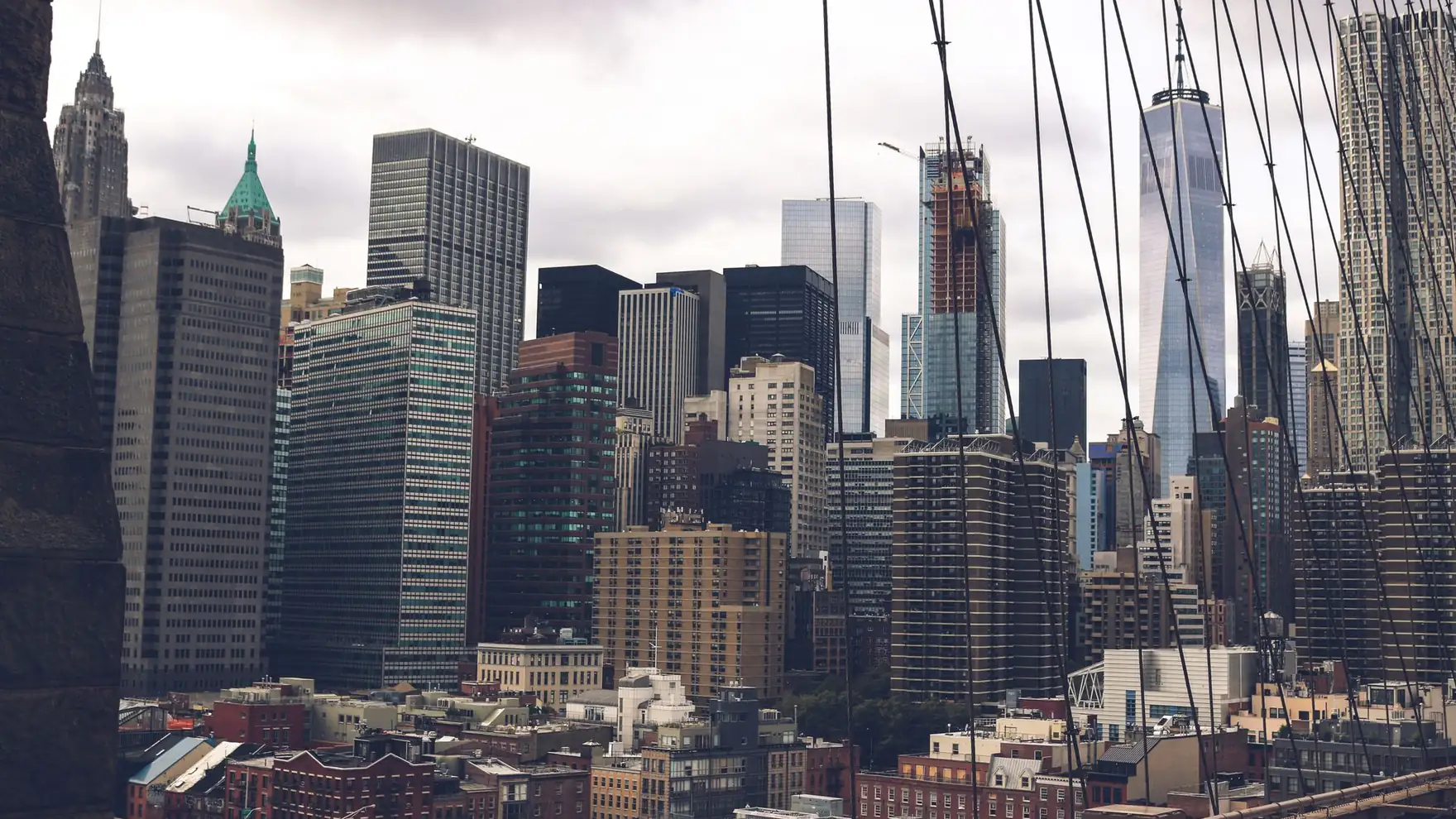 A dramatic view of the skyscrapers of New York City captured from the Brooklyn Bridge