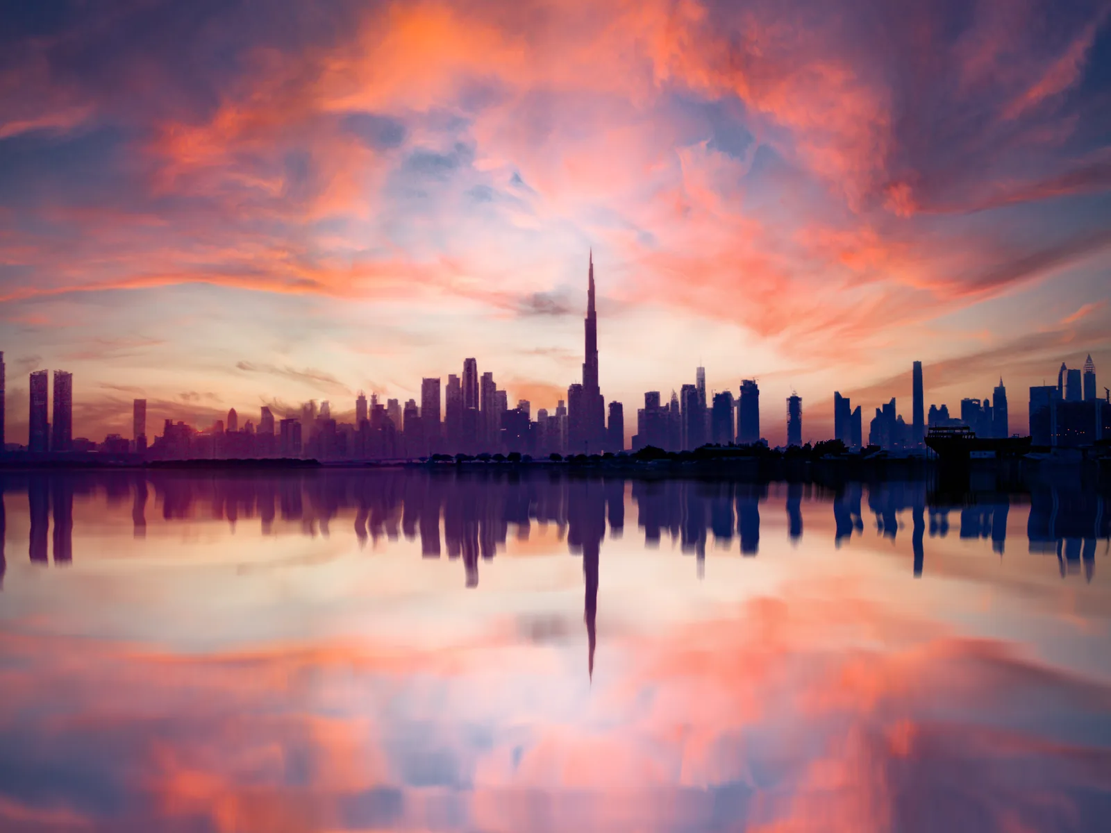 A breathtaking view of Dubai's skyline reflected in water during a vivid sunset, highlighting the urban architecture