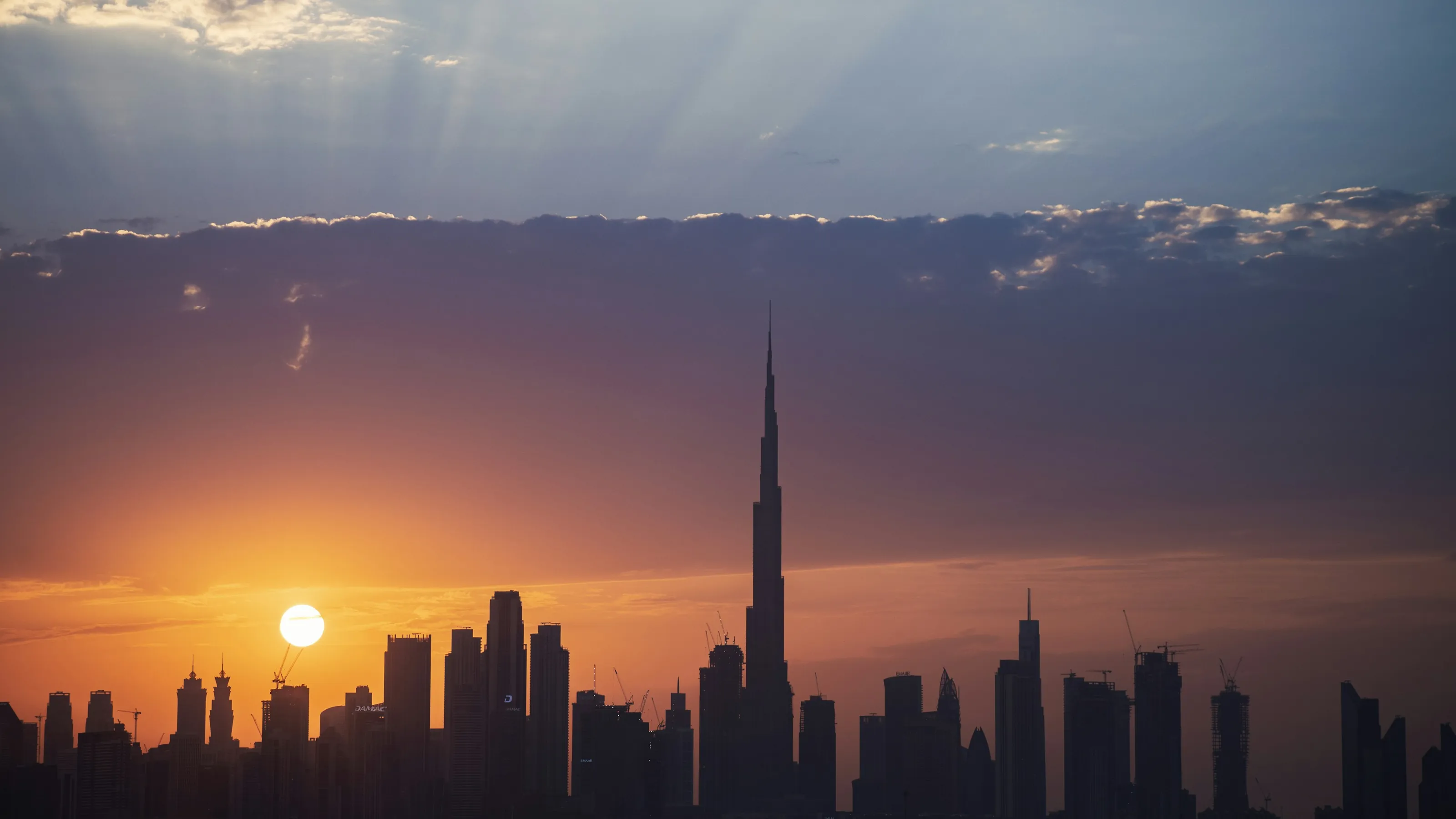 The Dubai skyline and Burj Khalifa in silhouette at sunset