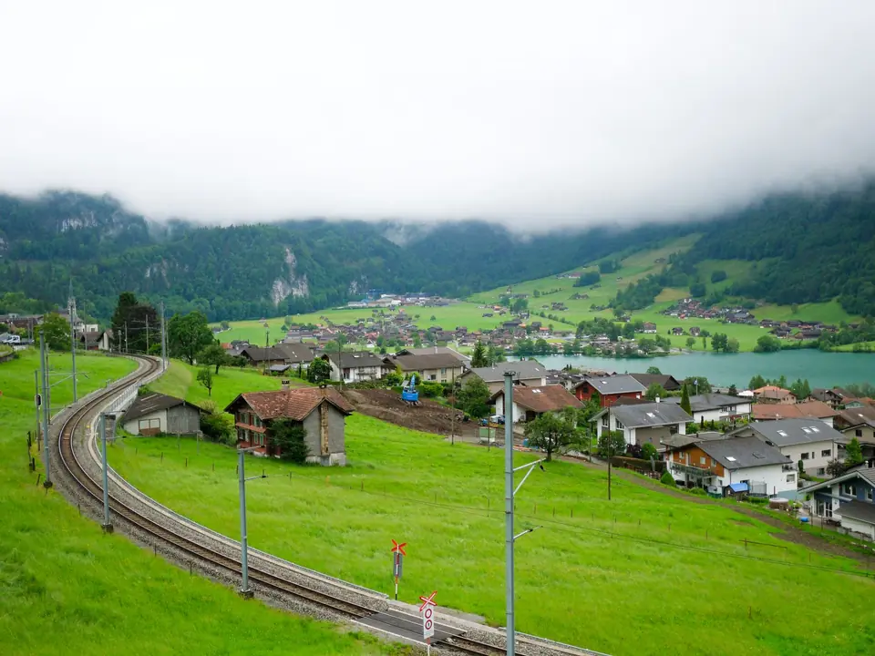 Beautiful shot of Lungern village in Switzerland with lush green hills and railway. Misty mountains in the backdrop