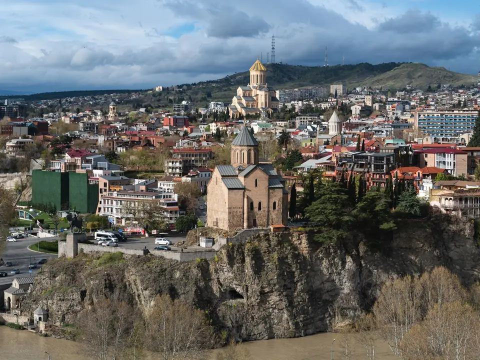 A panoramic view of Tbilisi, Georgia featuring historic churches and diverse architecture under a dramatic sky