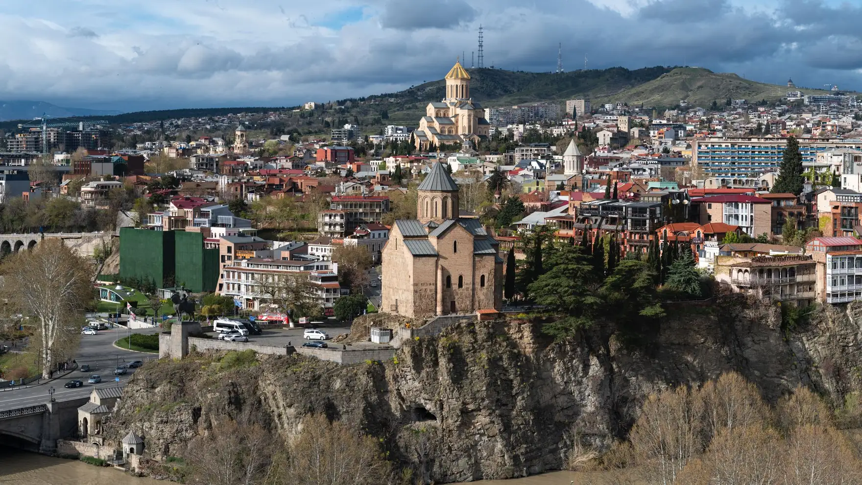 A panoramic view of Tbilisi, Georgia featuring historic churches and diverse architecture under a dramatic sky
