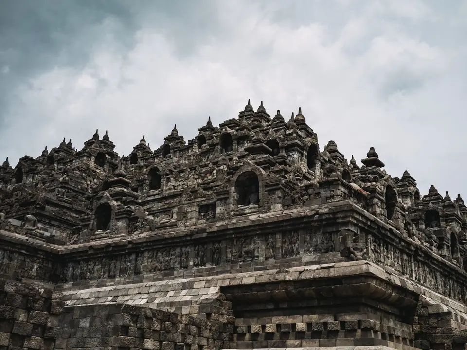 Majestic view of the ancient Borobudur Temple, showcasing intricate stone carvings under a cloudy sky