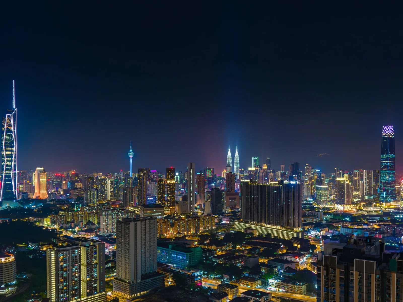 A vibrant night view of Kuala Lumpur's skyline featuring the iconic Petronas Towers