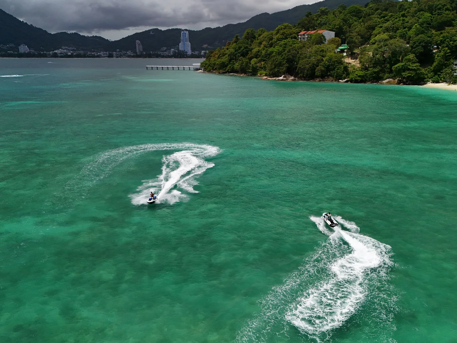 Dynamic aerial shot of jet skis on turquoise waters of Patong Beach, Phuket