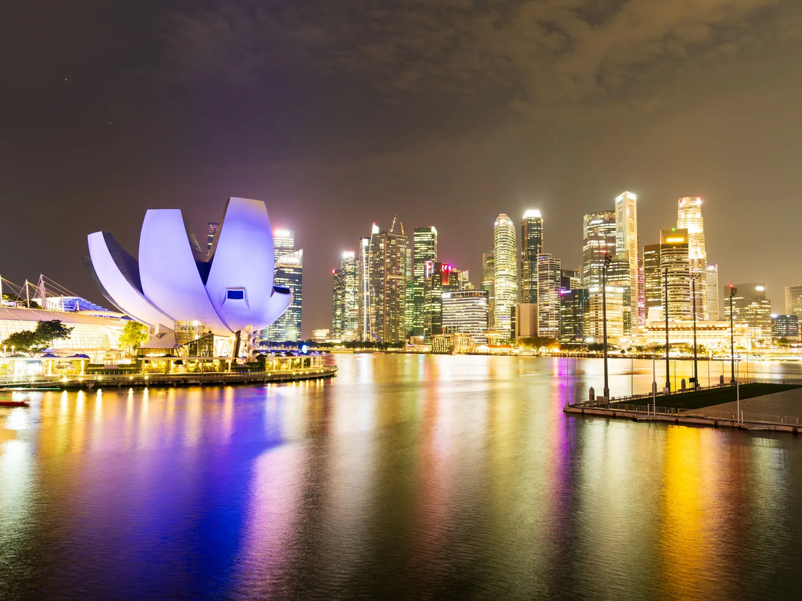 Night view of Singapore's illuminated skyline and Marina Bay Sands, reflecting vibrant city lights