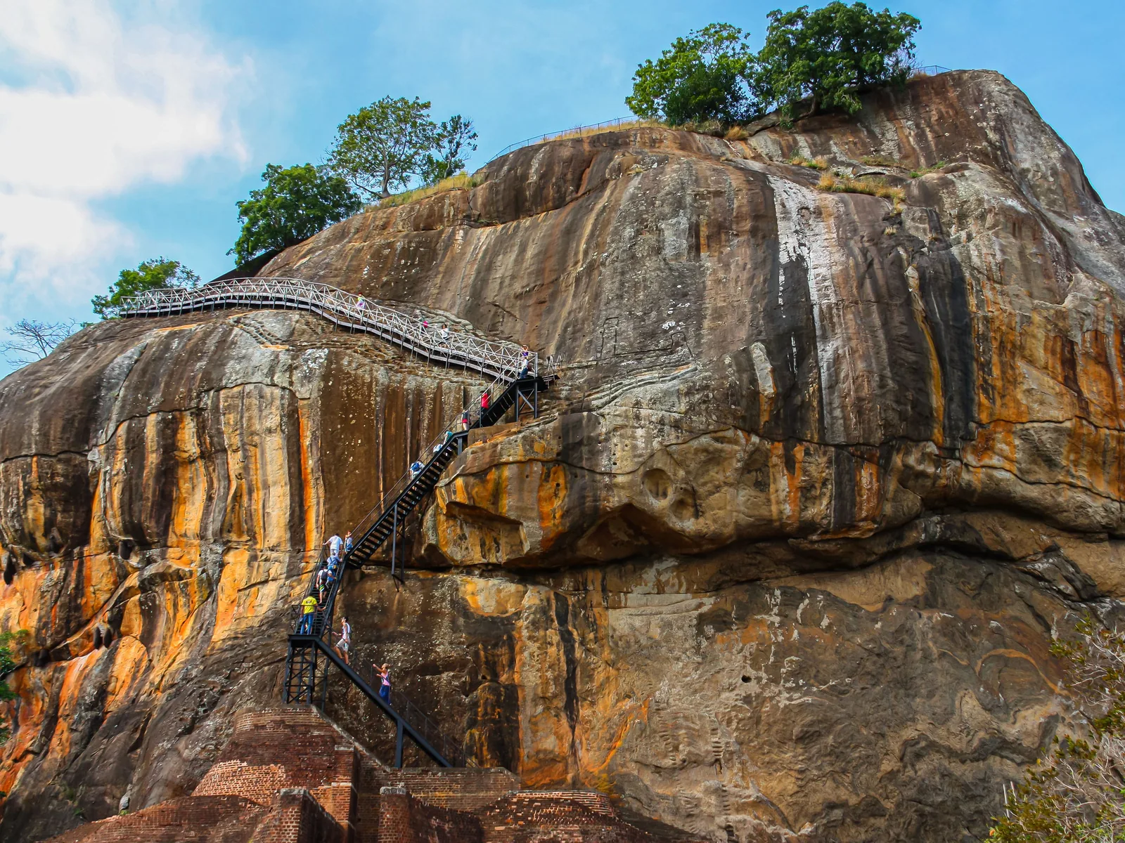 A breathtaking view of Sigiriya Rock Fortress, a UNESCO World Heritage site in Sri Lanka, with stairs and tourists ascending