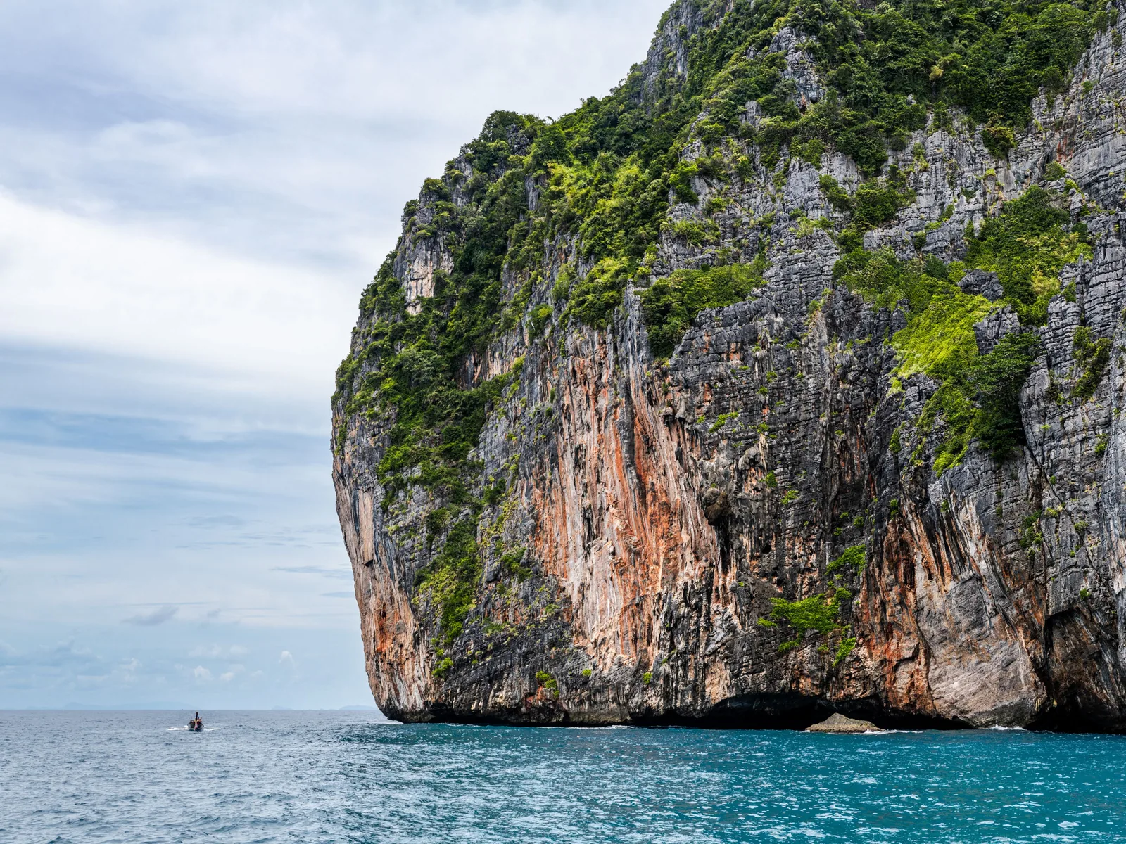 Majestic cliff rising from turquoise sea under a clear sky in Phuket, Thailand