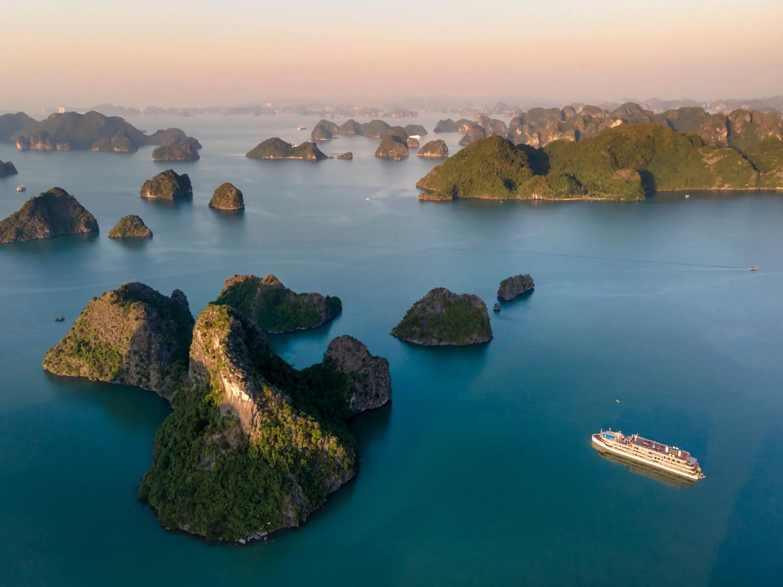 Stunning aerial view of Ha Long Bay's limestone karsts and cruise ship during sunrise