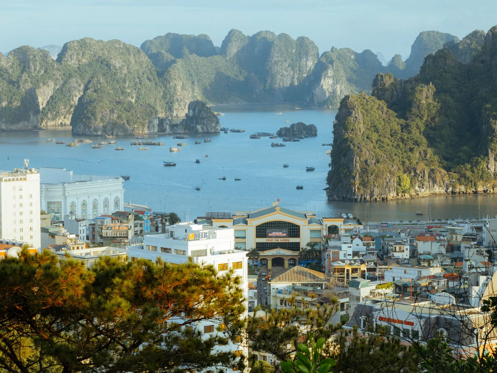 A stunning aerial view of Ha Long Bay, showcasing limestone karsts and urban landscape